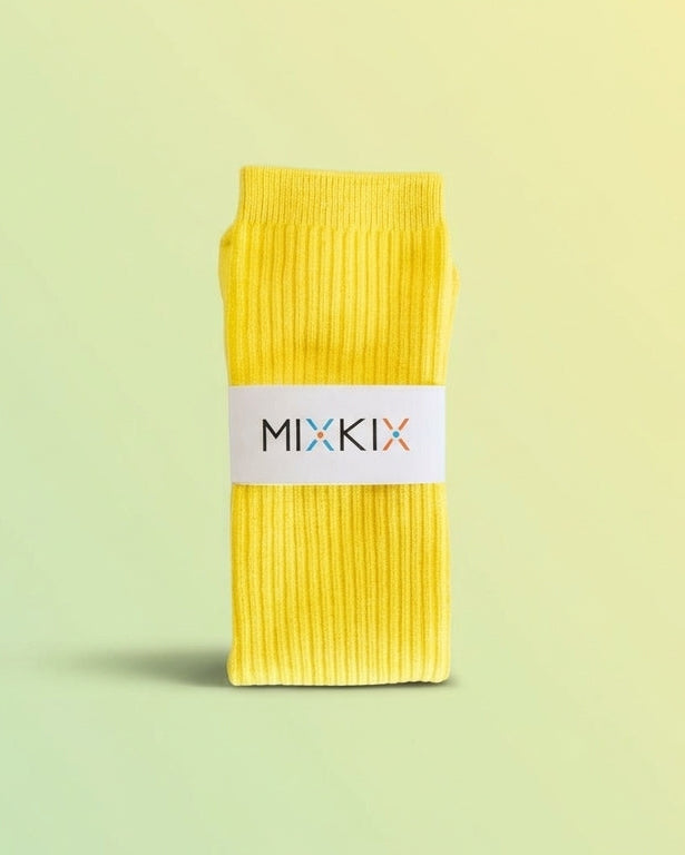 Yellow ribbed slouch socks for kids with a white paper band packageing around the middle reading 'MIXKIX'