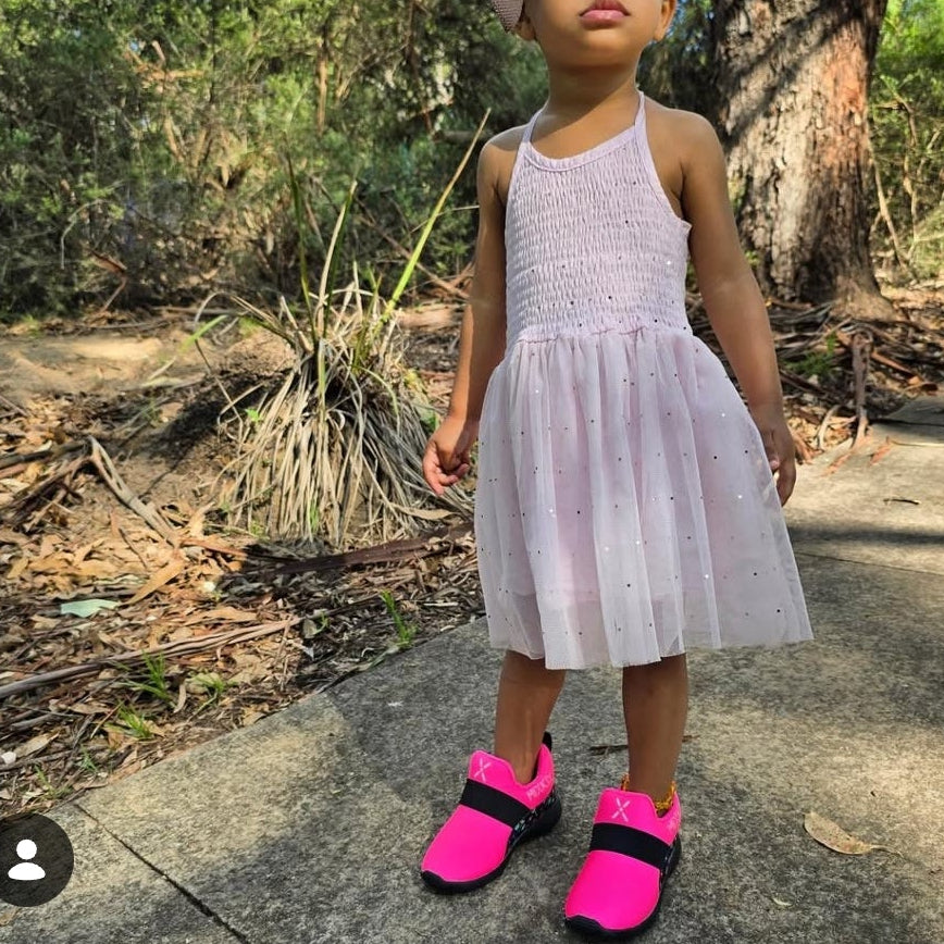A child wearing bright pink shoes by. Mix Kix