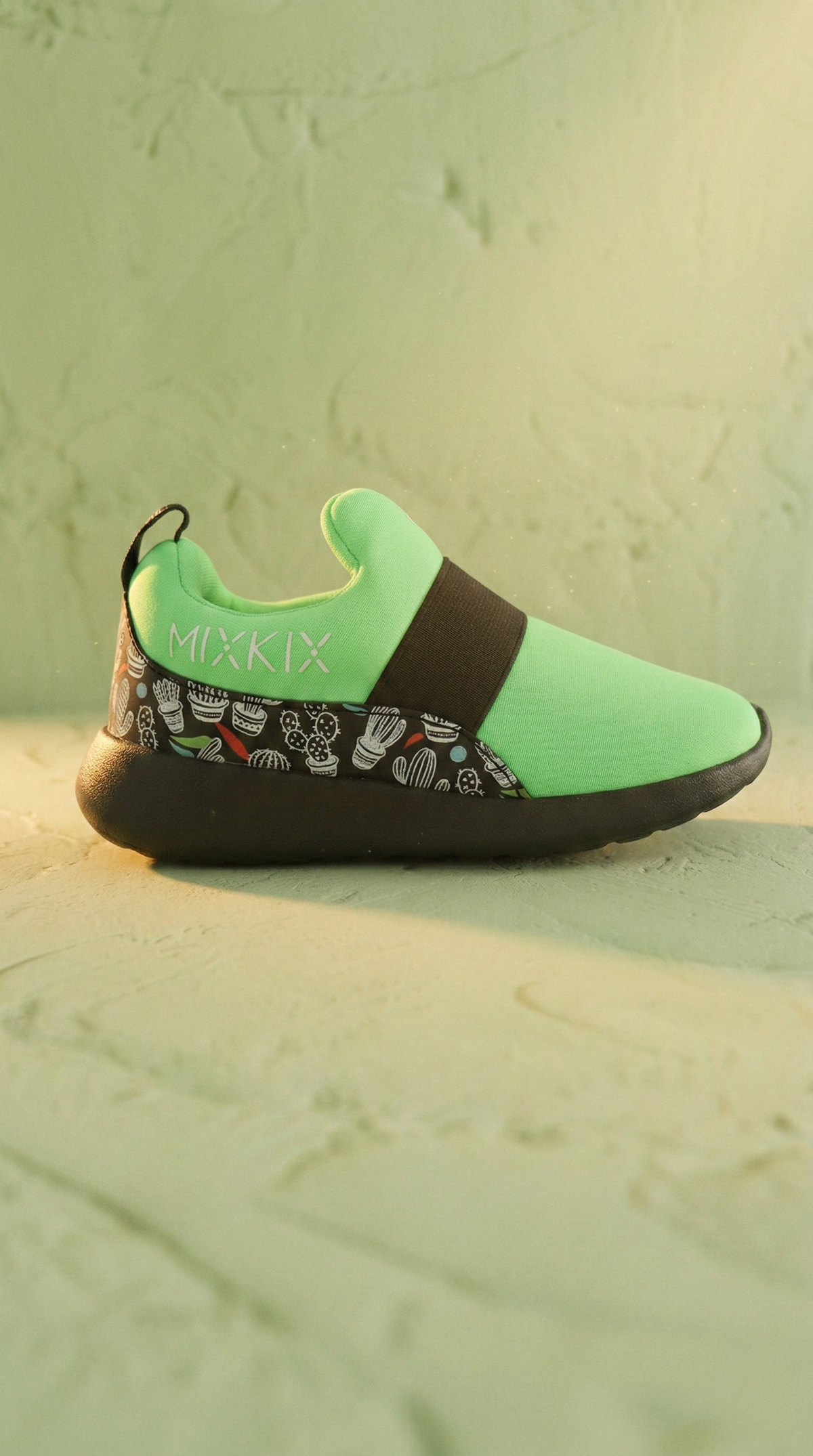 Green slip-on shoe with black strap on a textured surface