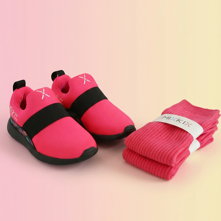 Pink children's shoes with black soles and matching socks on a gradient background